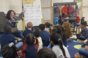 students sitting on the floor with a teacher in front