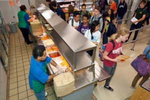 Students with trays get food in a school cafeteria.