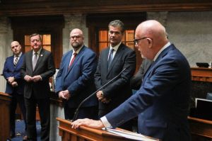 A line of lawmakers look on as one of their colleagues speaks at a lectern on the Indiana Senate floor.