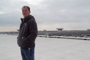 Tyler Gerardot stands in front of the solar array he helps maintain on top of Sweetwater Sound's distribution center in Fort Wayne.