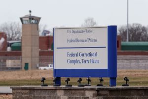 OK TO USE In this Dec. 10, 2019, file photo the guard tower flanks the sign at the entrance to the U.S. Penitentiary in Terre Haute, Ind.