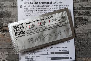 A piece of paper explaining how to use a fentanyl test strip, with the packaging that explains how to interpret the results of the test strip.