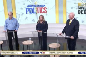 A screenshot of the WISH-TV gubernatorial debate. Jennifer McCormick, Mike Braun, and Donald Rainwater stand on the debate stage.