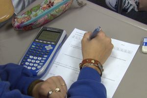 Student working on math homework with calculator