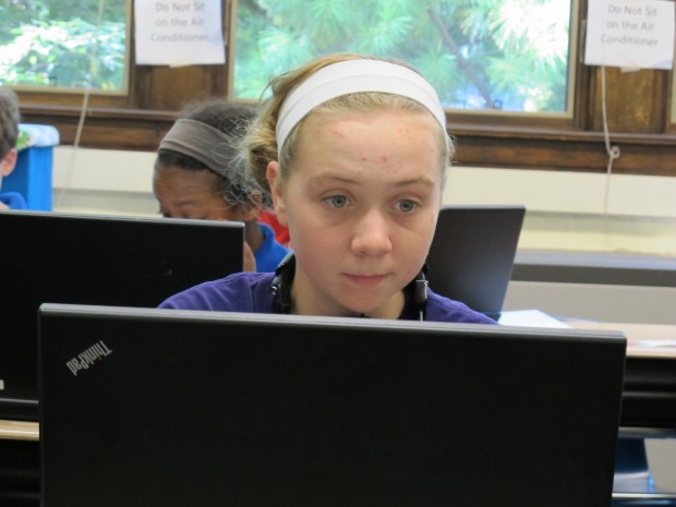 A seventh grader works on a laptop owned by her school in the classroom.